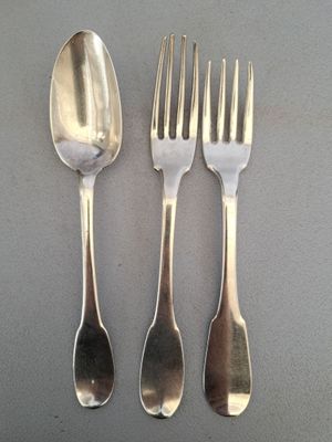 trois cuillères en argent et deux fourchettes en argent sur une table