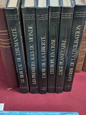 several books are stacked on a table in front of a pile of books