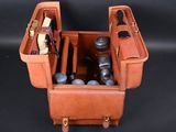 a brown leather case with a camera and other items in it