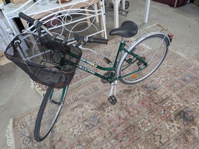 a bicycle with a basket attached to it sitting on a rug