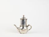an old silver teapot on a white surface with a white background