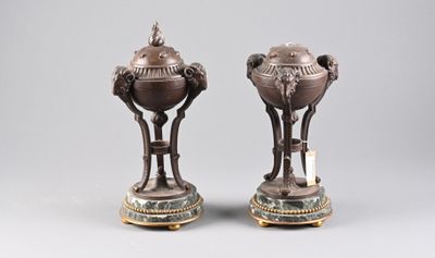 pair of bronze vases with handles on stands on a gray surface