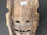 a close up of a wooden mask with a tag on it