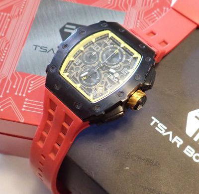 La montre est rouge et noire, avec un cadran jaune.
