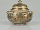 a gold and white bowl with a lid on a white surface