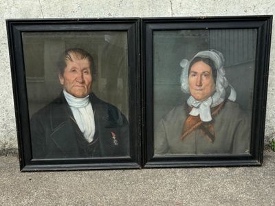 Deux portraits encadrés représentant un homme et une femme sont posés l'un à côté de l'autre