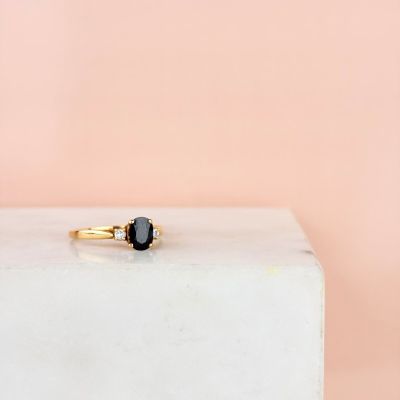 une bague en or sertie d'un diamant noir sur un bloc blanc
