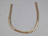 gros plan d'un collier en or sur une surface blanche
