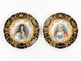 deux assiettes noires et dorées représentant le portrait d'une femme et d'un homme