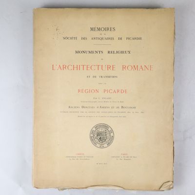 un vieux livre posé sur une table à côté d'un mur blanc