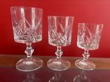 three wine glasses sitting on top of a table next to a red wall