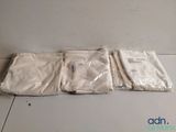 trois sacs en tissu blanc posés sur une table blanche