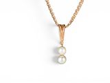 a gold necklace with two pearls on a chain
