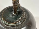 an image of a bronze bell with a twisted handle on a white surface