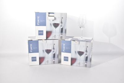 trois cartons de vin posés sur une table, à côté d'un verre de vin