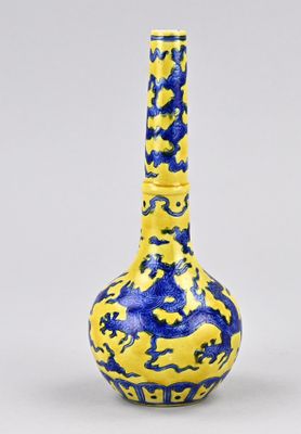 un vase jaune et bleu posé sur une surface blanche, sur fond gris