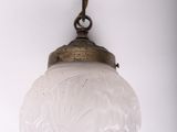 an antique brass and frosted glass hanging light fixture on a chain