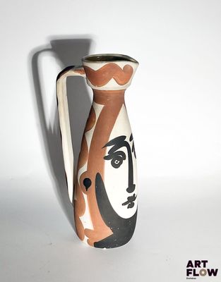 a vase with a face painted on it sitting on a table