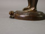 bronze statue of a woman holding a flower on a pedestal