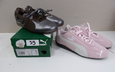 deux paires de chaussures Puma posées sur une boîte, elle-même posée sur une table