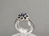 bague en argent sterling sertie de saphirs bleus et de diamants, posée sur un socle en acrylique transparent