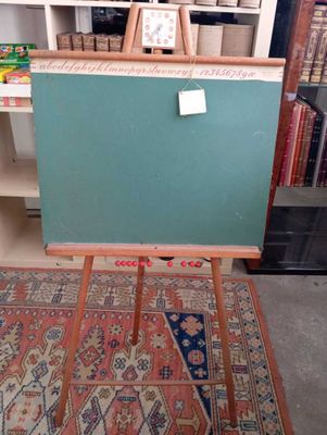 un tableau noir posé sur un chevalet en bois devant une bibliothèque