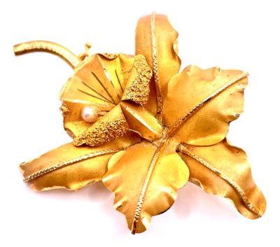 broche en forme de fleur en or, ornée de perles et de feuilles sur fond blanc