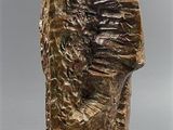 sculpture of a man ' s head on a rock on a gray surface