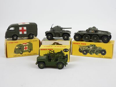 Quatre véhicules militaires miniatures sont posés dans une boîte sur une surface blanche