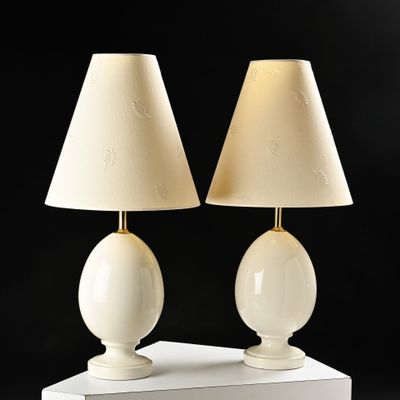 two white lamps on a white table with a black background