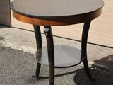 a small round table with a wooden top on the sidewalk