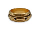 un gros plan d'une bague en or sertie de deux pierres noires