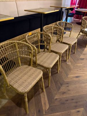 Plusieurs chaises en osier sont alignées les unes à côté des autres dans un restaurant