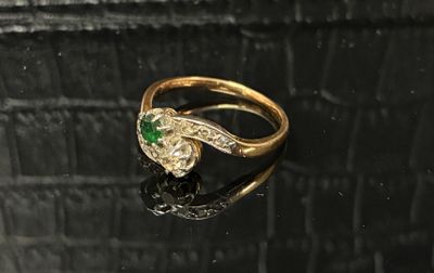 gros plan d'une bague en or avec une pierre verte