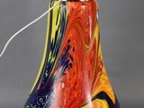 brightly colored glass lamp with a metal base and a white light bulb