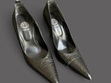 two pairs of black shoes with silver heels on a gray surface