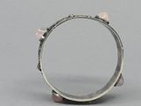 silver ring with pink stones on top of it on a gray surface