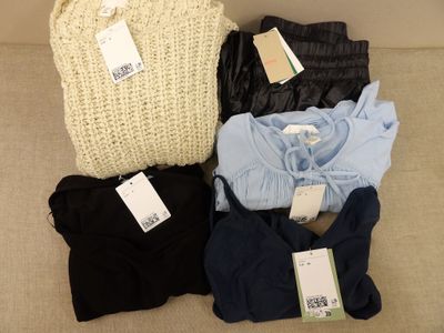 quatre paires de vêtements pour femmes posées sur un canapé, avec leurs étiquettes encore attachées