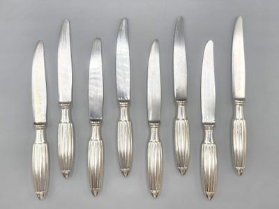 six silverplated knives and a knife holder on a table