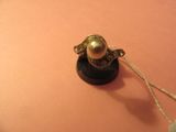 une bague en or sertie d'une perle, posée sur un fond rose