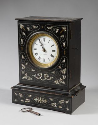 a black clock with a gold and white design on it