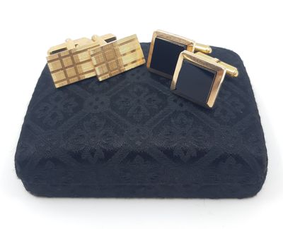 a pair of black and gold cufflinks sitting on top of a blue blanket
