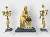 a statue of a woman holding a clock next to three candelabs