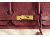 a close up of a red leather handbag with a gold lock