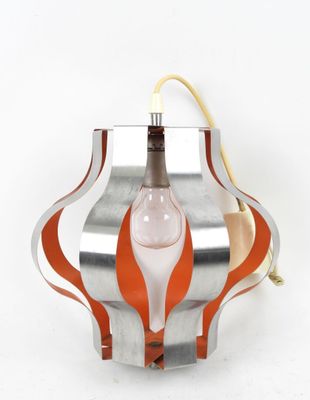 an orange and silver lamp hanging from a wall on a white background