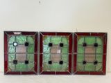trois vitraux aux encadrements rouges et verts sur un fond blanc