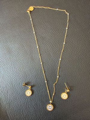 un ensemble composé d'un collier et de boucles d'oreilles, avec une pièce de monnaie posée sur un fond noir