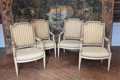 trois chaises blanches placées devant un mur sur lequel est accrochée une peinture