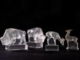 three clear glass figurines of animals on a black surface