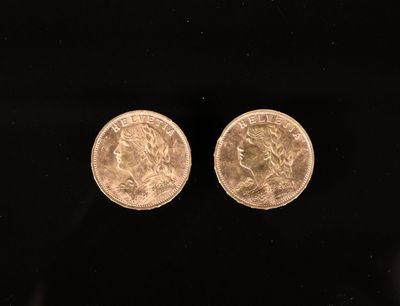une paire de deux pièces d'or posées sur une surface noire